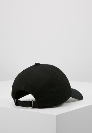 Casquette de baseball noire ajustable reposant sur une surface blanche, vue de dos avec la sangle et la boucle métallique visibles.