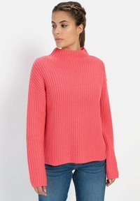 Roze geribde trui met hoge nek, lange mouwen en een ontspannen pasvorm. Gemaakt van een zachte, gestructureerde breimateriaal.