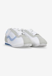 Zapatillas blancas y grises con un acento en azul claro. Hechas de cuero y materiales sintéticos, con una suela texturizada y un diseño de cordones.