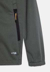 Veste grise avec une poche zippée dotée d'une languette jaune, des poignets élastiques et un logo "A.W.S. Active" blanc sur l'ourlet. Texture lisse.