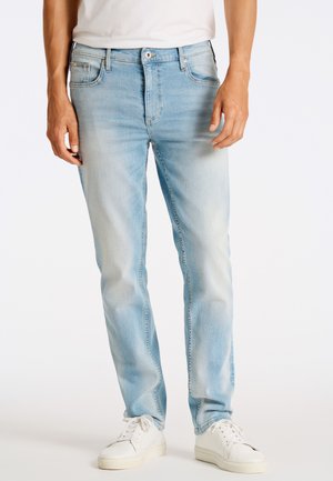 Jeans din denim de un albastru deschis, cu o croială drepte, având cinci buzunare și o închidere cu buton în față, asortați cu teniși albi.