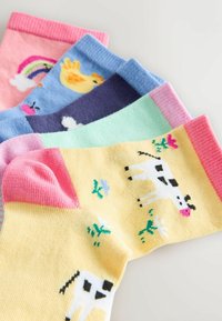Vijf kleurrijke kindersokken met een koe op geel, een eend op blauw, een regenboog op roze en andere speelse ontwerpen.
