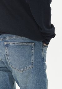 Kratek jeans v svetlo modri barvi, s klasičnim pet-pocket dizajnom. Mehka tekstura, vidni šivi, s ravnim krojem hlačnic, kot je vidno zadaj.