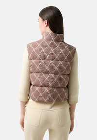 Materiałowy, wzorzysty kamizelka w kolorze bordowym i kremowym, z wysokim kołnierzem i pikowanym wzorem. Noszona na jasnoszarym, długim rękawie topie.