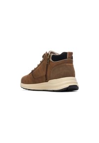 Botas de cuero marrón hasta el tobillo con una superficie texturizada, cremallera lateral y una suela acolchada de color crema; diseñadas para ofrecer comodidad y soporte.