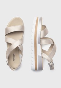 Sandali platform dorati metallici con design a cinturino incrociato, tomaia texturizzata e una suola bianca spessa con una striscia di accento marrone.