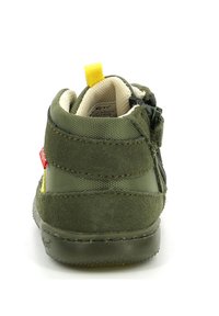 Zapato infantil verde de ante y malla con un collar acolchado, tira amarilla para tirar y cremallera lateral para facilitar el uso. Suela de goma con agarre texturizado.