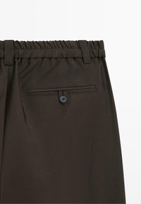 Dark brown trousers with an elastic waistband, belt loops, and a back welt pocket secured by a single button.