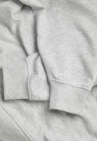 Pelēka jaka ar mīkstu audumu, ar salocītām piedurknēm un ribotām aprocēm. Materiāls ir nedaudz melnīgsnā, ar vieglu heather efektu.