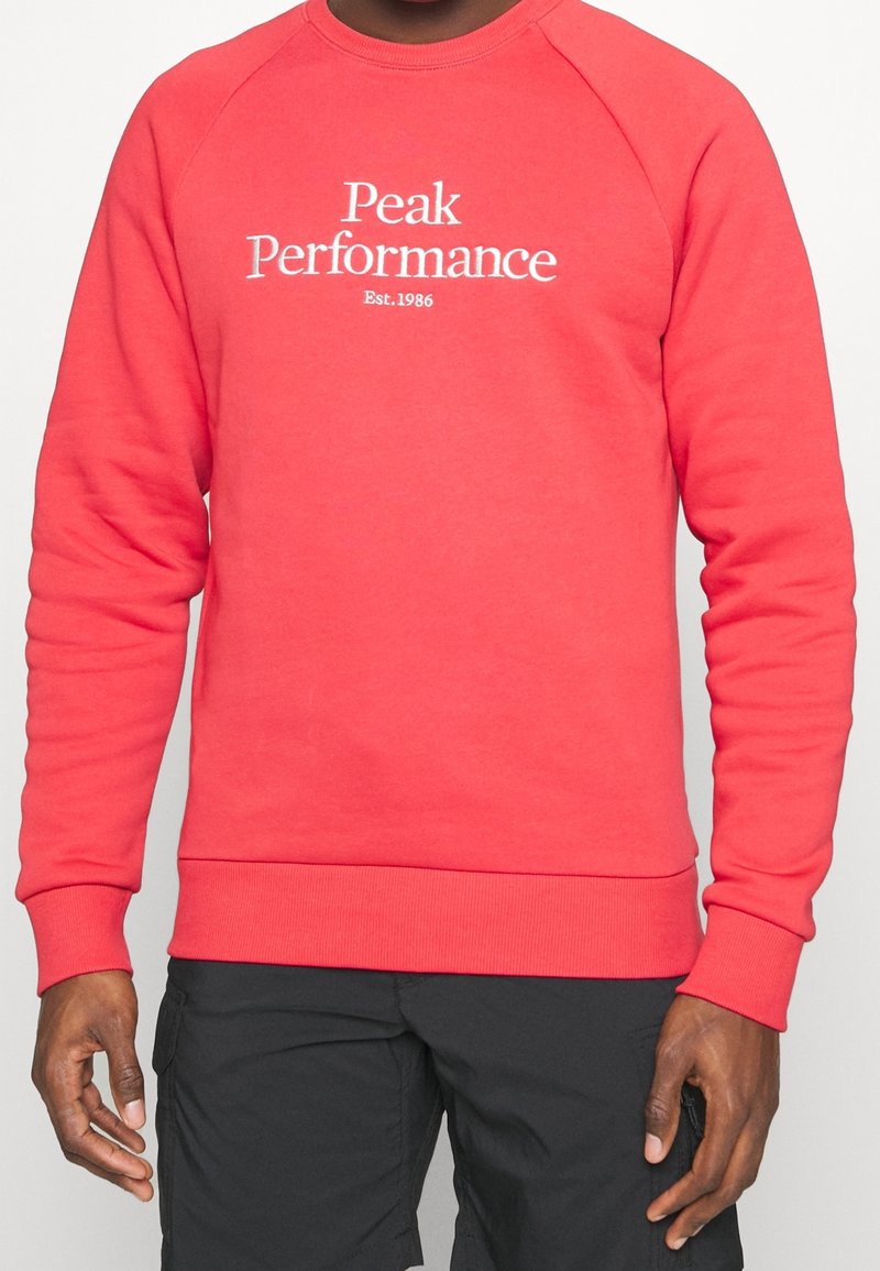 Rode sweatshirt met ribgebreide boorden en onderrand, voorzien van het "Peak Performance"-logo in het wit op de voorkant, gemaakt van zachte stof.