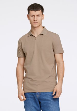 Polo en color beige con cuello tipo placket y mangas cortas, hecho de una tela suave, combinado con jeans de mezclilla azul. Diseño liso sin patrones.