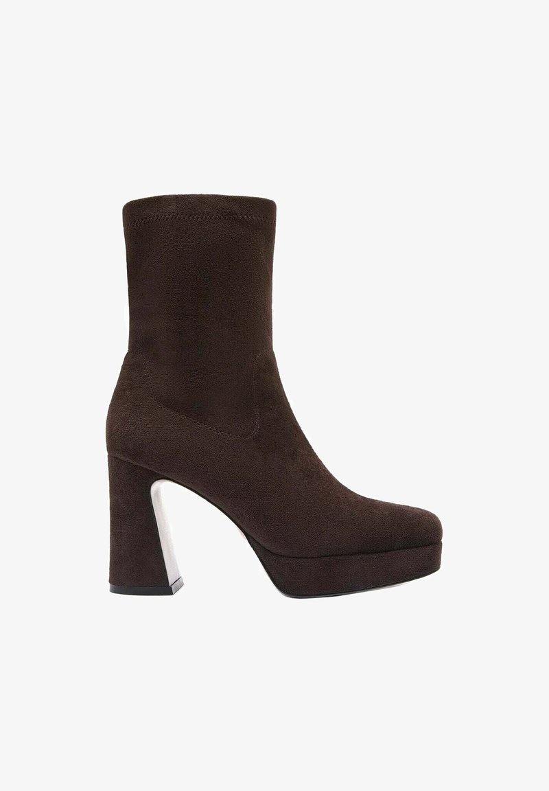 Stivaletto in suede marrone con punta arrotondata, suola platform e tacco spesso con un accento argentato. Texture liscia, design minimalista.