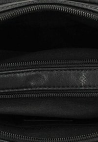 Sort lynlås håndtaske med flere rum, fremstillet af glat læder og tekstilmaterialer, med kontrasterende lynlås detaljer.