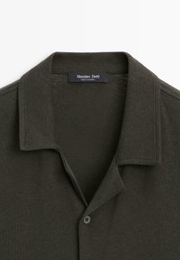 Dark green collared shirt with button closure and Massimo Dutti label sewn inside the neckline, made in Cambodia.