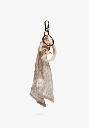 Sciarpa di seta beige con motivo, attaccata a un portachiavi dorato con ciondoli color crema di forma circolare e astratta.