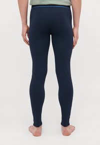 Marina stretchleggings med en tajt design, slät textur och ett blått midjeband; vy från baksidan som visar ankellånga manschetter.