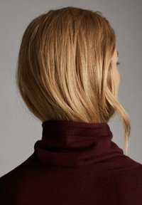 Burgundy turtleneck-neule, jossa on ribbikolla, pehmeä rakenne ja tiukka muoto, esitetty takaa hiusten valuessa alas.