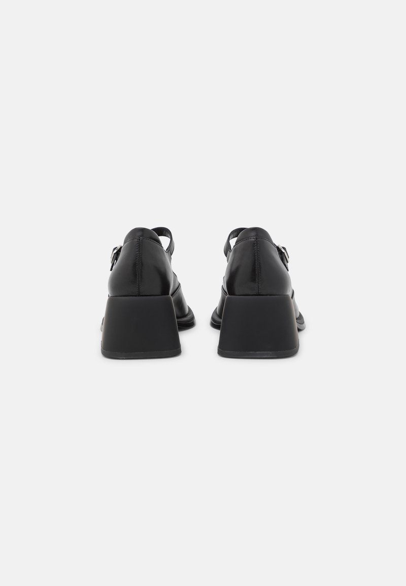 Talons en cuir noir avec un design compensé, dotés d'une sangle à l'arrière et d'une texture lisse. Le talon est carré et entièrement noir.