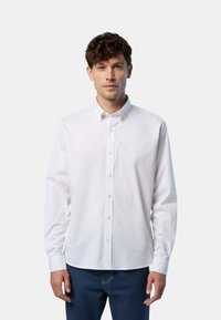 Camicia bianca con collo classico, maniche lunghe e un piccolo logo sul lato sinistro del petto. Il tessuto sembra liscio e intrecciato.