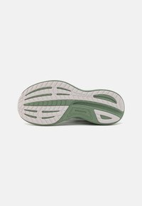 Semelle de chaussure de sport en vert et blanc. Présente un motif de semelle texturé pour l'adhérence, avec un talon arrondi et un détail de logo sur le côté.