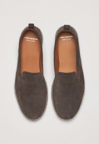 Grå ruskinds slip-on sko med en syet sål. Indvendig har de brunt læder. Mærket læser "FRED MARTIN MADE IN SPAIN."