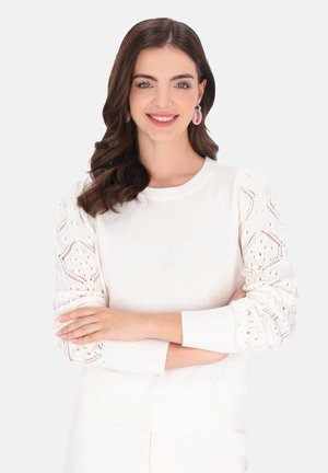 Hvid sweater med lange, strukturerede ærmer med et dekorativt strikkemønster. Selve kroppen er glat og ribbet ved manchetterne og kanten.