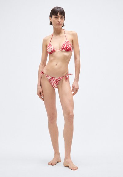 Biquíni vermelho e branco com padrão, apresentando um top triangular e cuecas com lateral de amarrar, feito de tecido macio com detalhes mínimos de hardware.