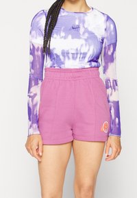 Långärmad, lila tie-dye topp med "AIR"-logotyp; matchad med rosa shorts med broderad detalj. Mjuk, elastisk tyg.
