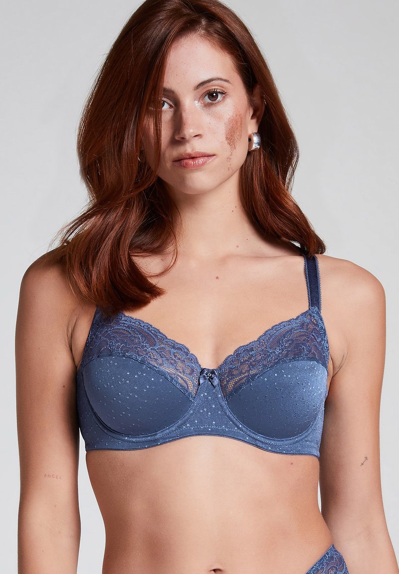 Donderblauwe beha met beugels, versierd met kant aan de bovenrand, met een stippenstructuur op de cups en een klein strikje in het midden.