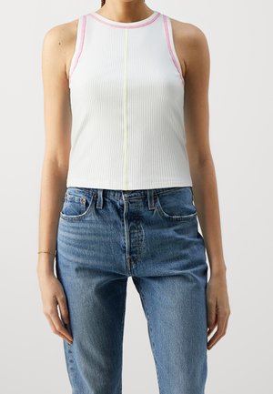 Biały prążkowany top na ramiączkach z różowo-żółtymi detalami przeszyć, zestawiony z niebieskimi wysokim stanem jeansami. Bawełniany materiał, dopasowany krój, krótka długość.