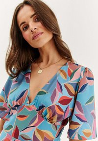 Šaty s květinovým vzorem a hlubokým V výstřihem, krátkými nabíranými rukávy. Barvy zahrnují modrou, růžovou, červenou, zelenou a oranžovou na světlém pozadí.