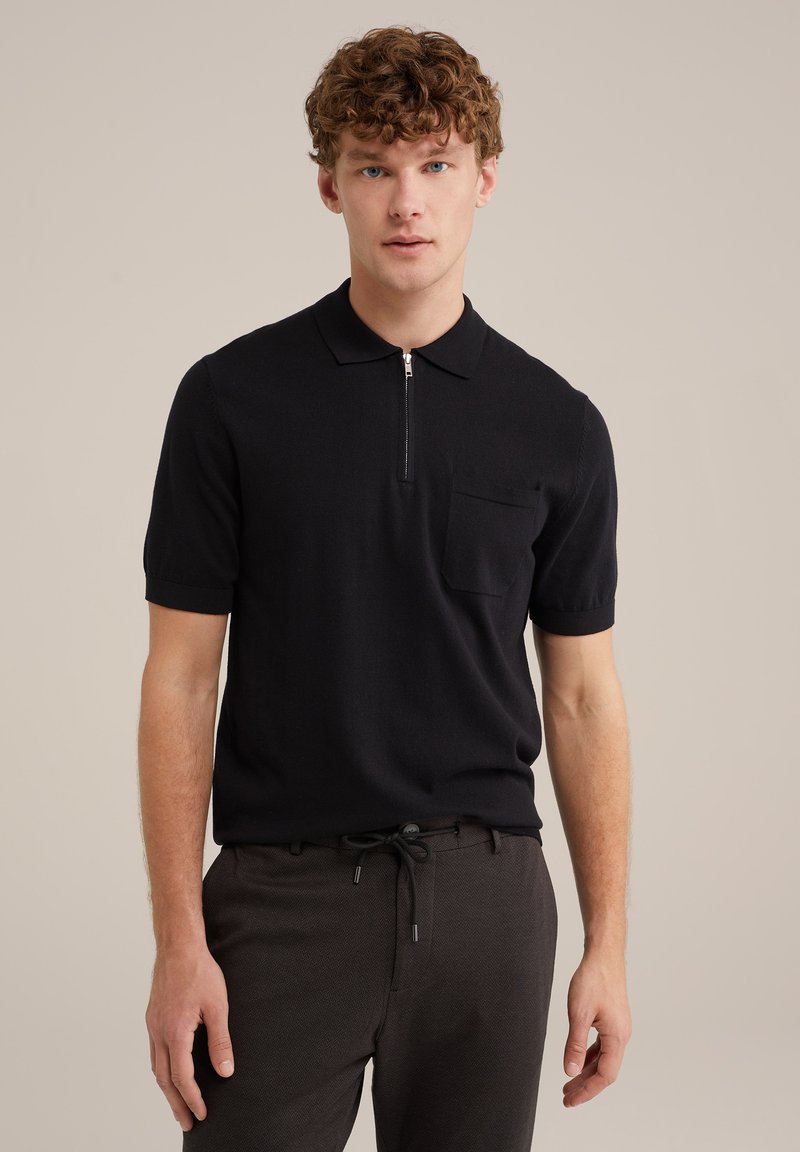 Black short-sleeve polo shirt made of knit fabric, featuring a zippered collar and a chest pocket, paired with dark pants.