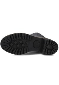 Suela de bota de goma negra con un patrón de banda de rodadura robusto, que presenta formas de diamante y un diseño cruzado para mayor tracción. La entresuela tiene un ligero aumento.
