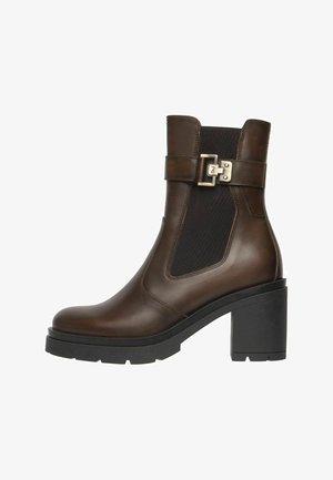 Brown leather ankle boot with black elastic side panel, silver buckle strap, chunky black block heel, and textured sole.