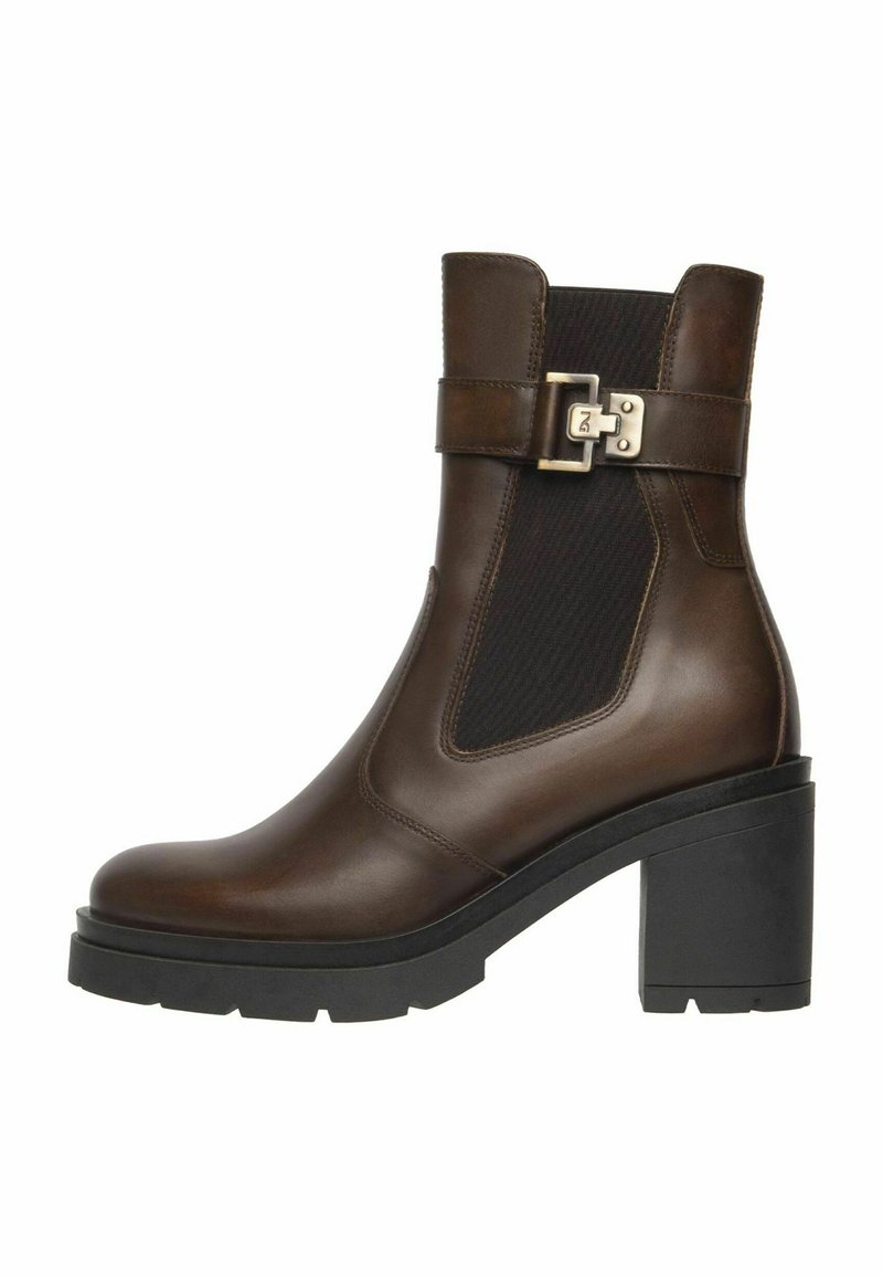 Botte en cuir marron avec panneau élastique noir sur les côtés, sangle à boucle argentée, talon carré noir épais et semelle texturée.