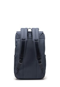 Mörk marinblå ryggsäck med två vadderade axelremmar, frontfack med dragkedja och texturerad tyg. Liknande rektangulär form med minimalistisk design.