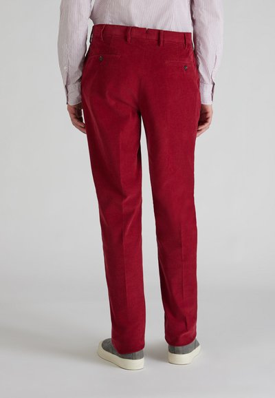 Pantalones de pana roja con un corte recto y bolsillos laterales, que presentan una textura suave y sutiles detalles de costura, combinados con zapatos grises.