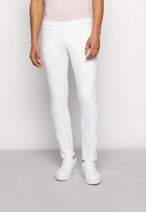 Witte denim jeans, slim fit, met een gladde textuur. Voorzien van vijf zakken en een ritsluiting. Gecombineerd met witte sneakers.