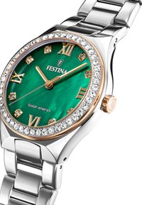 Hodinky Festina s zeleným ciferníkem, římskými číslicemi a zlatými akcenty. Stříbrný kovový náramek, kulatá pouzdro s krystalovým rámečkem a solární pohon.