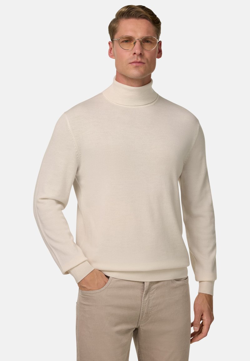Krēmkrāsas turtlenecks džemperis mīkstā adījumā, pieguļošs dizains, ar garām piedurknēm un ribotām pieturēm, apvienots ar gaišām bēžām biksēm.