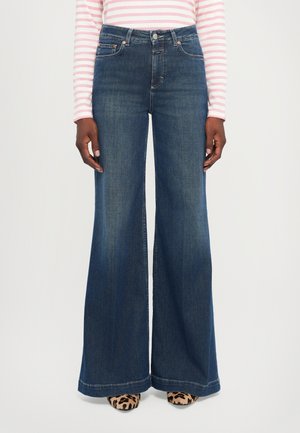 Ullnende mørkeblå jeans med frontlommer og beltehemper. Har høy midje og vid benpassform, kombinert med sko i dyreprint.