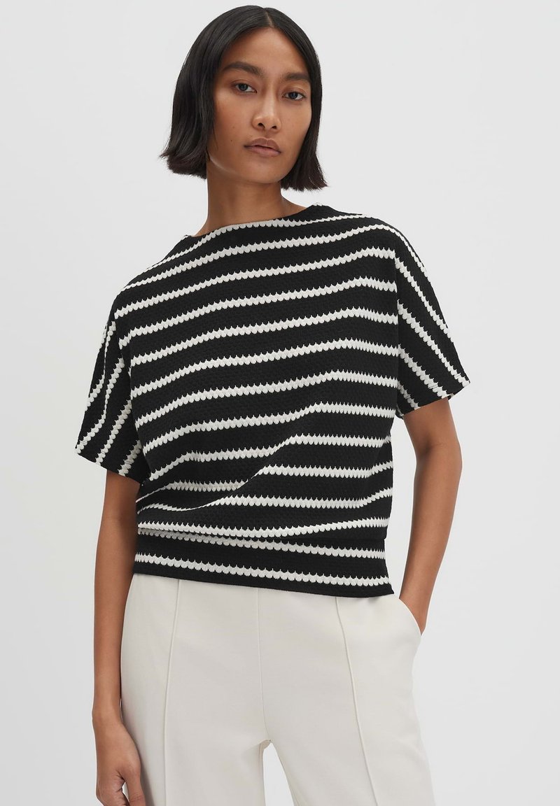 Zwart-wit gestreepte short-sleeve trui in een luxe breisel, met een losse pasvorm en een brede halslijn. Gekoppeld aan lichte pantalons.