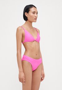 Roza rebrasta bikini s trikotno zgornjo stranjo in visokimi hlačkami, ki ima tanke naramnice in gladko teksturo.