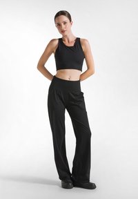 Zwarte cropped tanktop met een ronde halslijn, gecombineerd met zwarte wijde broek met hoge taille en zijzakken.