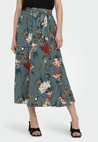 Blomster midi nederdel i sred, med bindebånd i taljen, livlige røde, hvide og gule blomster samt en flydende silhuet med en blød tekstur.