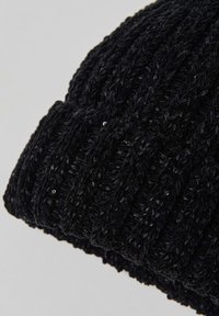 Black knitted beanie made of soft yarn, featuring a textured braided pattern with subtle shiny accents, and a snug fit at the bottom.