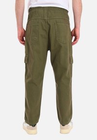 Pantaloni cargo verdi con un elastico in vita, due tasche posteriori e due tasche laterali cargo. Il tessuto è leggero e resistente.