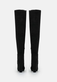 Stivali over-the-knee in suede nero con tacco grosso, caratterizzati da una trama liscia, design senza cuciture e una zip laterale per indossarli facilmente.