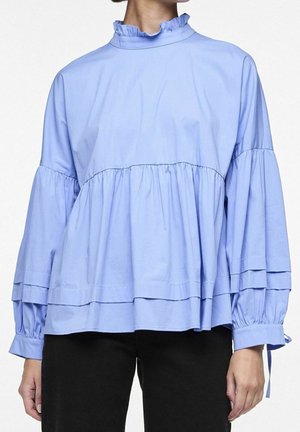 Hellblaue lose Bluse mit gerafftem hohen Kragen, taillierter Taille und langen Puffärmeln, getragen zu schwarzen Hosen.