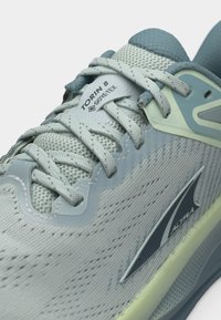 Ανοιχτό γαλάζιο παπούτσι τρεξίματος Altra Torin 8 Gore-Tex με υφασμάτινο πλέγμα, χοντρά κορδόνια και λογότυπο της μάρκας στο πλάι και στη γλώσσα.